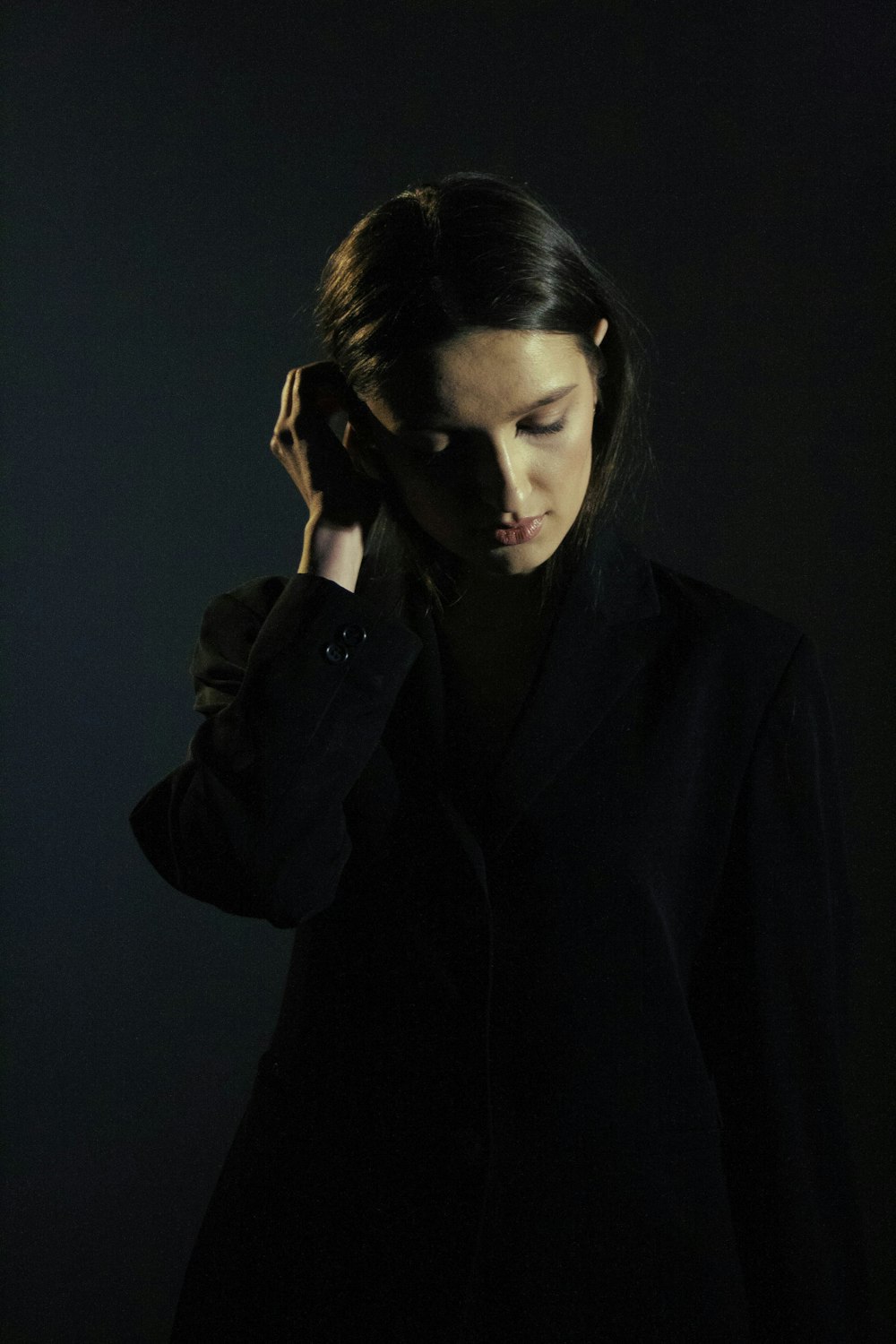a woman standing in the dark with her hand on her head