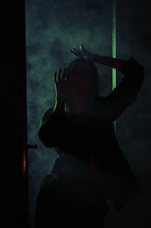 A cinematic shot of a character walking through smoke illuminated by red light.