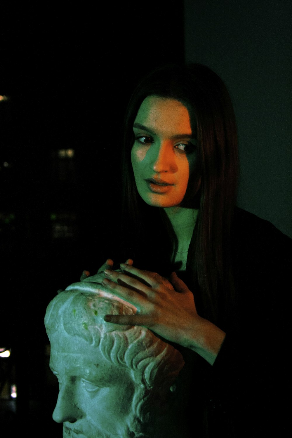 Una donna tiene in mano una statua nel buio