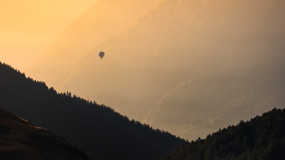 a hot air balloon flying over a mountain range