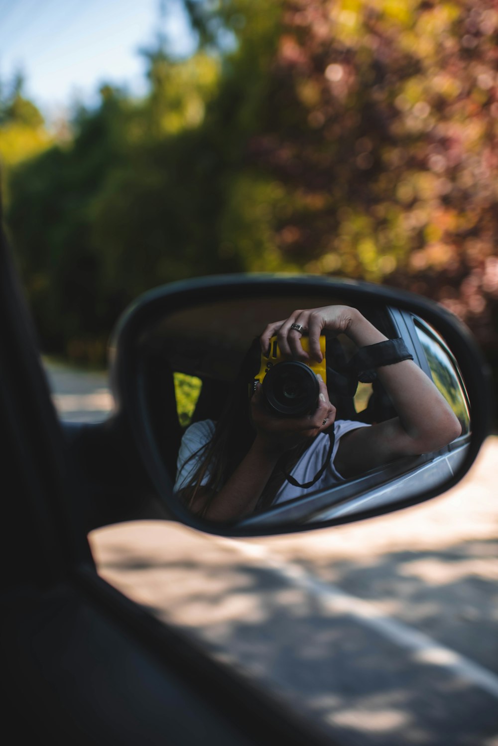 a woman taking a picture of herself in the side mirror of a car