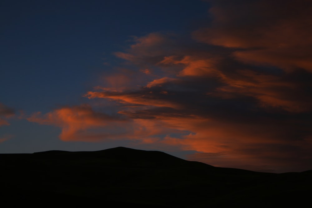 Una puesta de sol con nubes y montañas de fondo