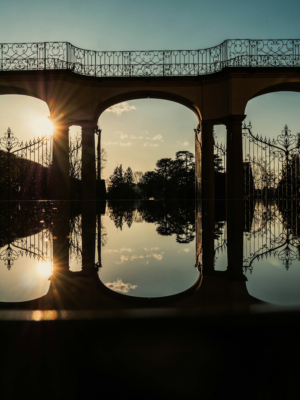 the sun is setting behind a bridge over a body of water