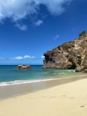 Close-up of Scivu Beach’s golden sands framed by dramatic cliffs under a clear blue sky.