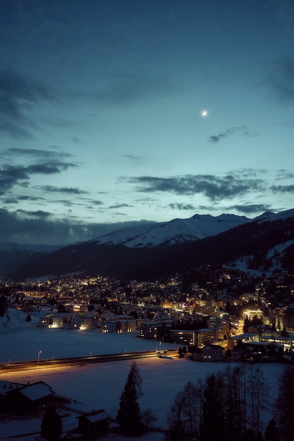 a city at night with a full moon in the sky