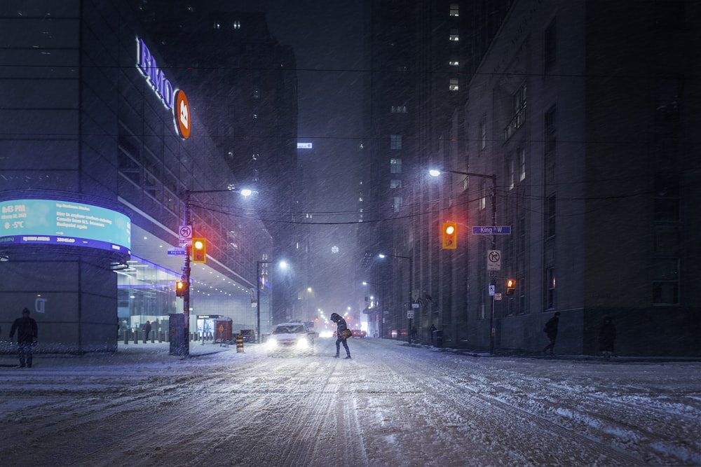 a couple of people walking across a snow covered street