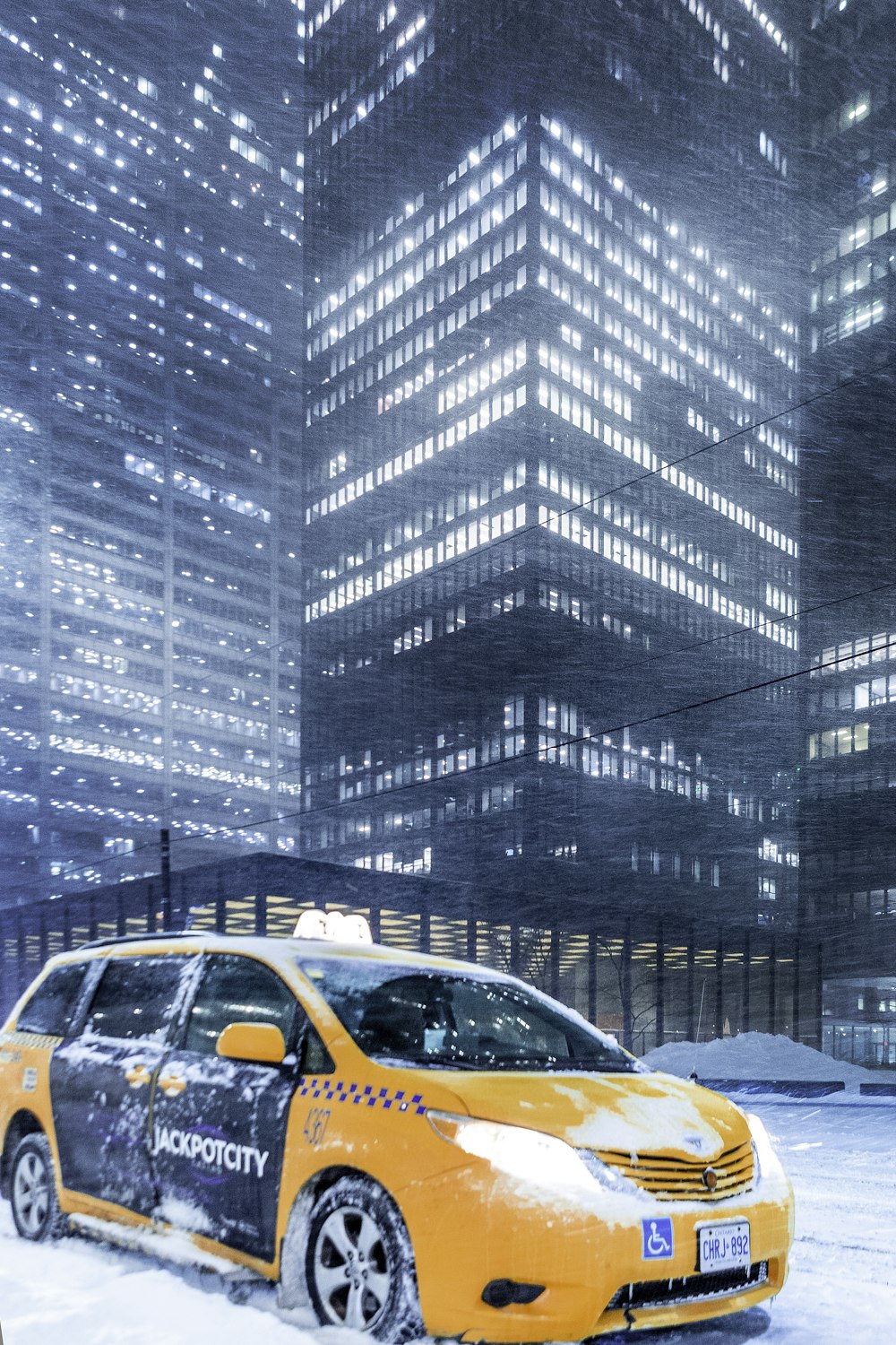a yellow taxi cab driving through a snow covered street