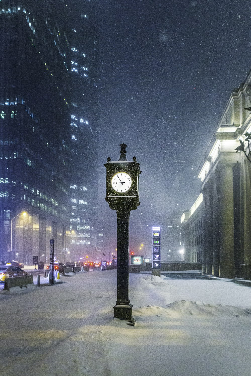 a clock in the middle of a snowy street