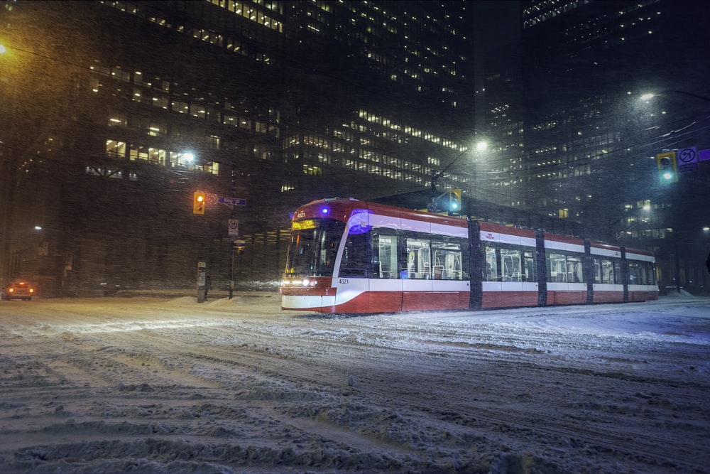 a red, white and blue train traveling through a city at night