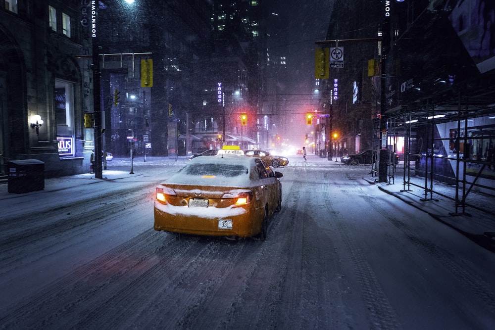 a car driving down a snow covered street at night
