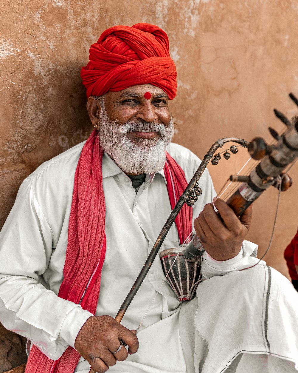 a man with a red turban playing a sitar