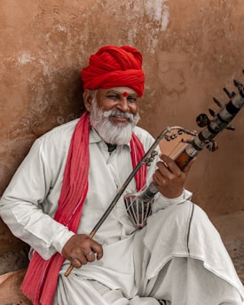 a man with a red turban playing a musical instrument