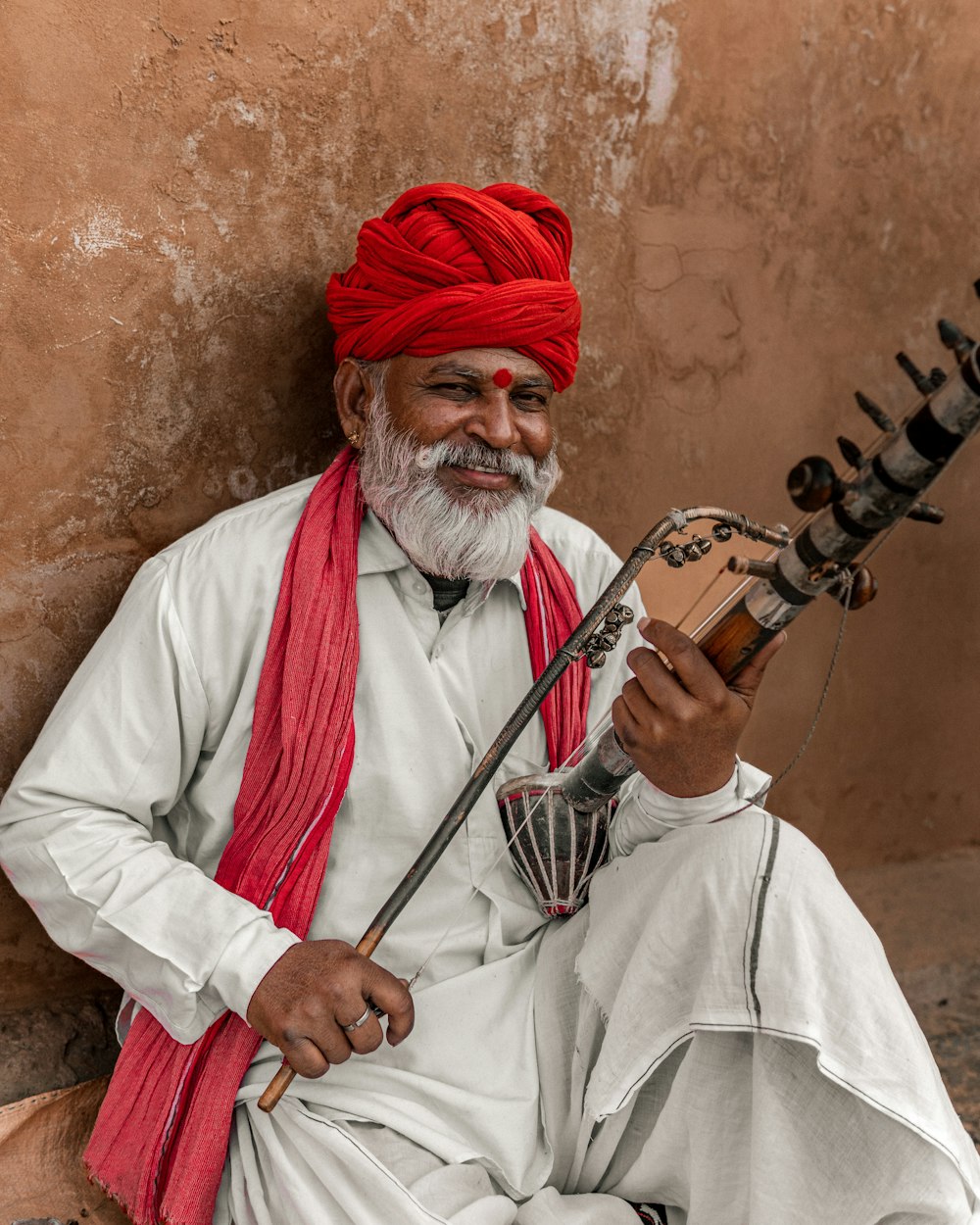 a man with a red turban playing a musical instrument