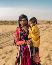 A Wayuu mother holding her child tenderly in the arid landscape of La Guajira.