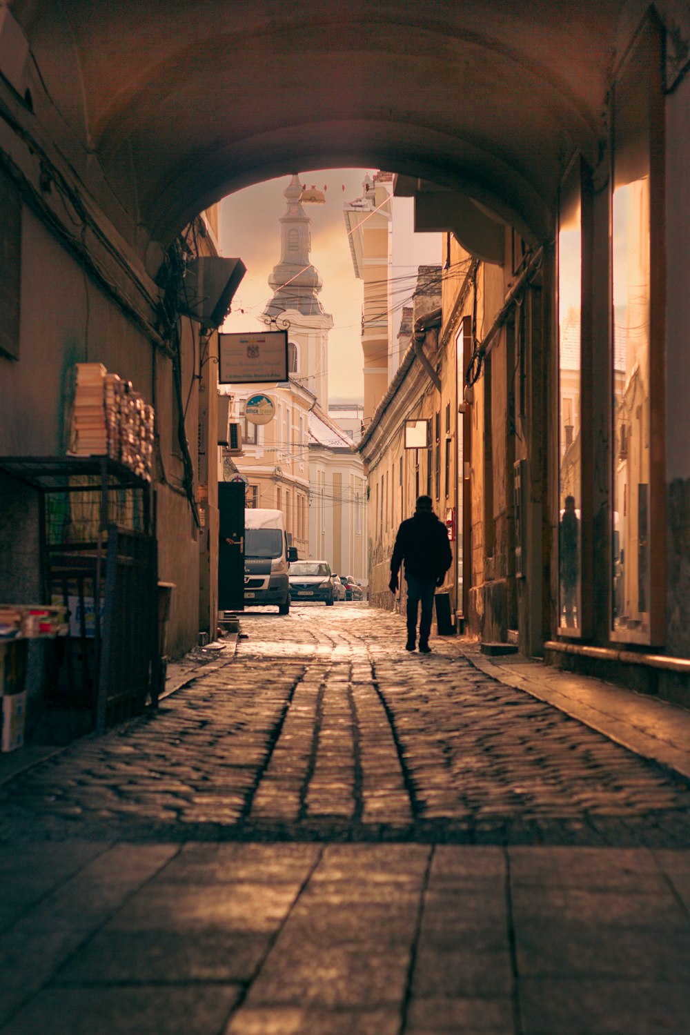 a man walking down a street next to tall buildings