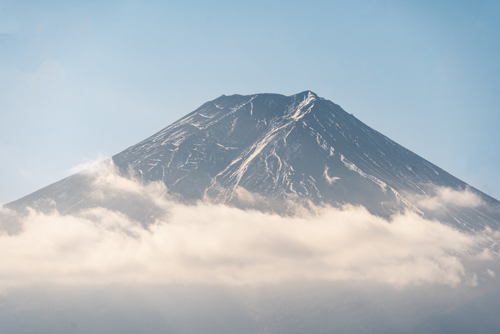 a large mountain covered in clouds under a blue sky