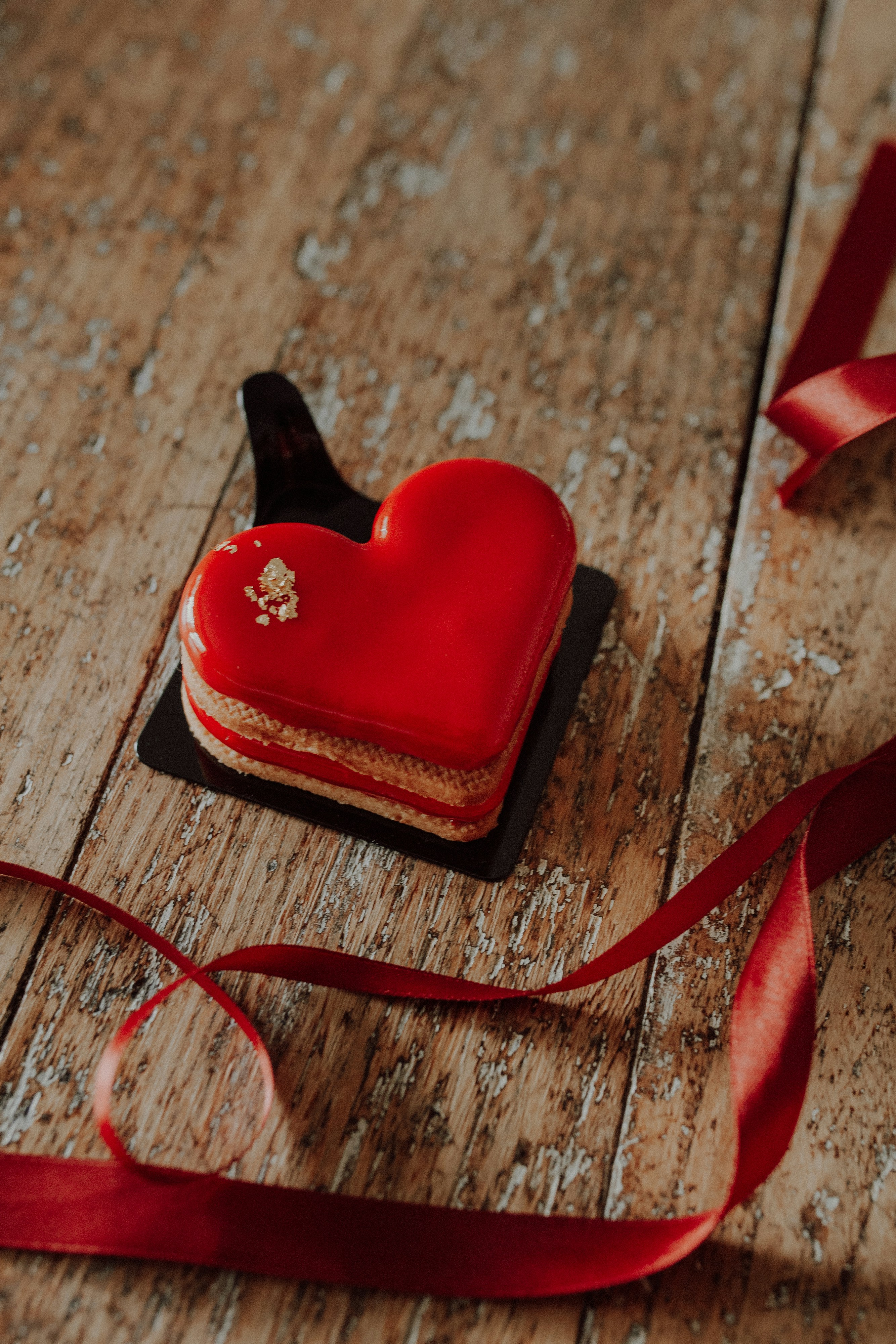 A red heart shaped cookie sitting on top of a wooden table photo – Free ...