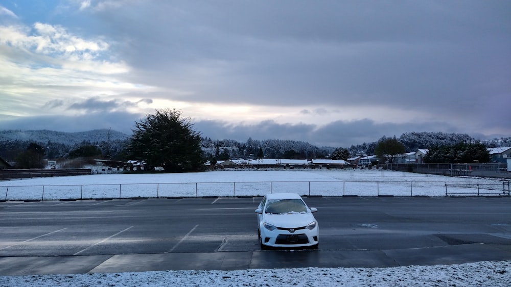 Un coche blanco estacionado en un estacionamiento cubierto de nieve