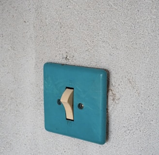 a blue light switch on a white wall