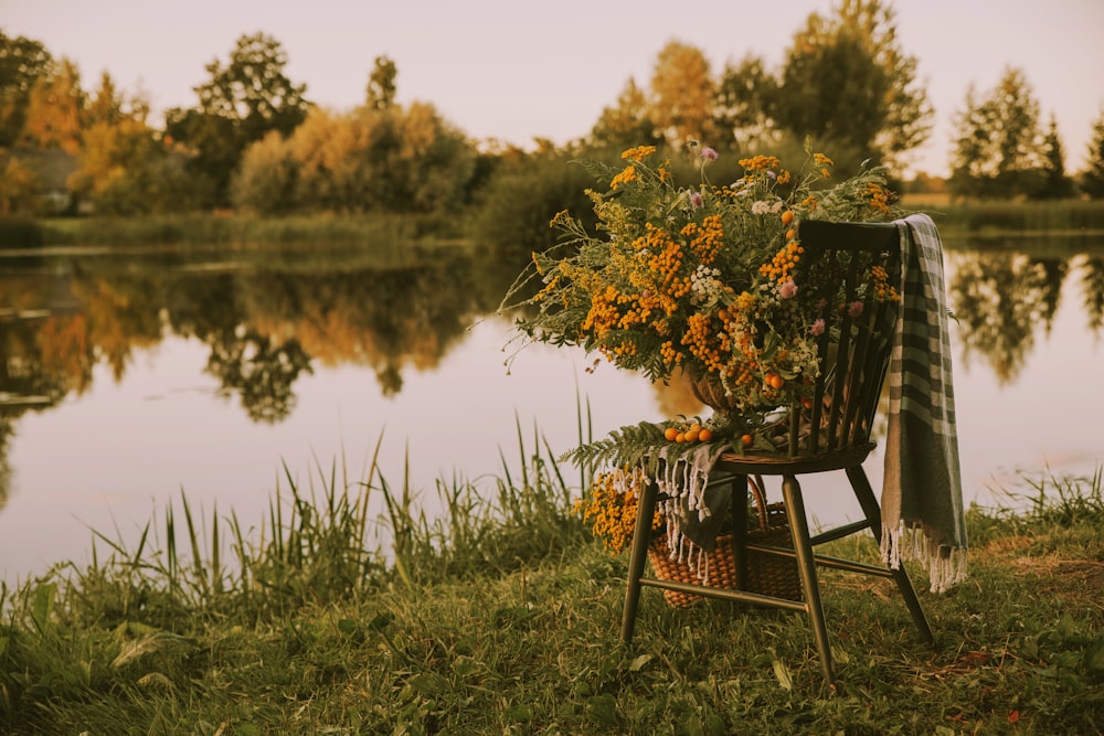 a chair with a bouquet of flowers on it by a lake