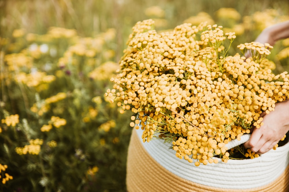 a person holding a basket full of yellow flowers