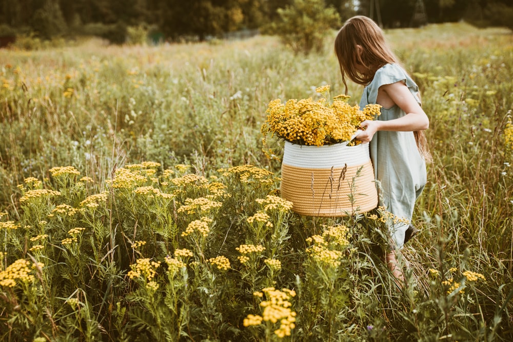 a girl in a field holding a basket of flowers