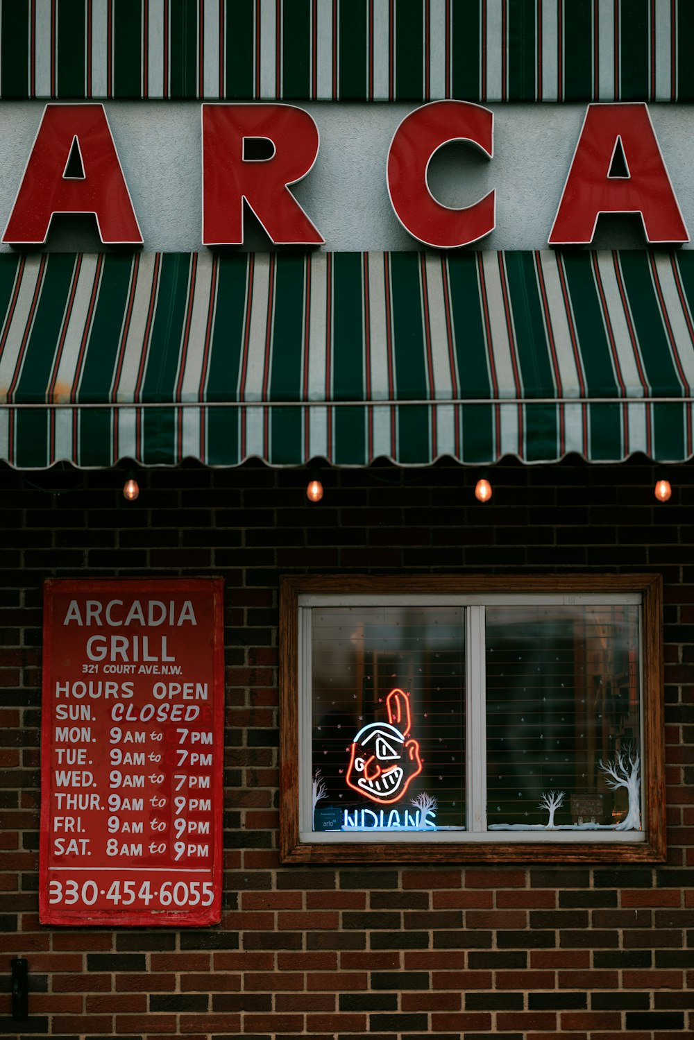 a brick building with a striped awning and a sign for arca