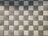 A pattern of square pavers arranged in a checkered layout with alternating light and dark shades of gray. The surface texture of each paver is rough and pebble-like.