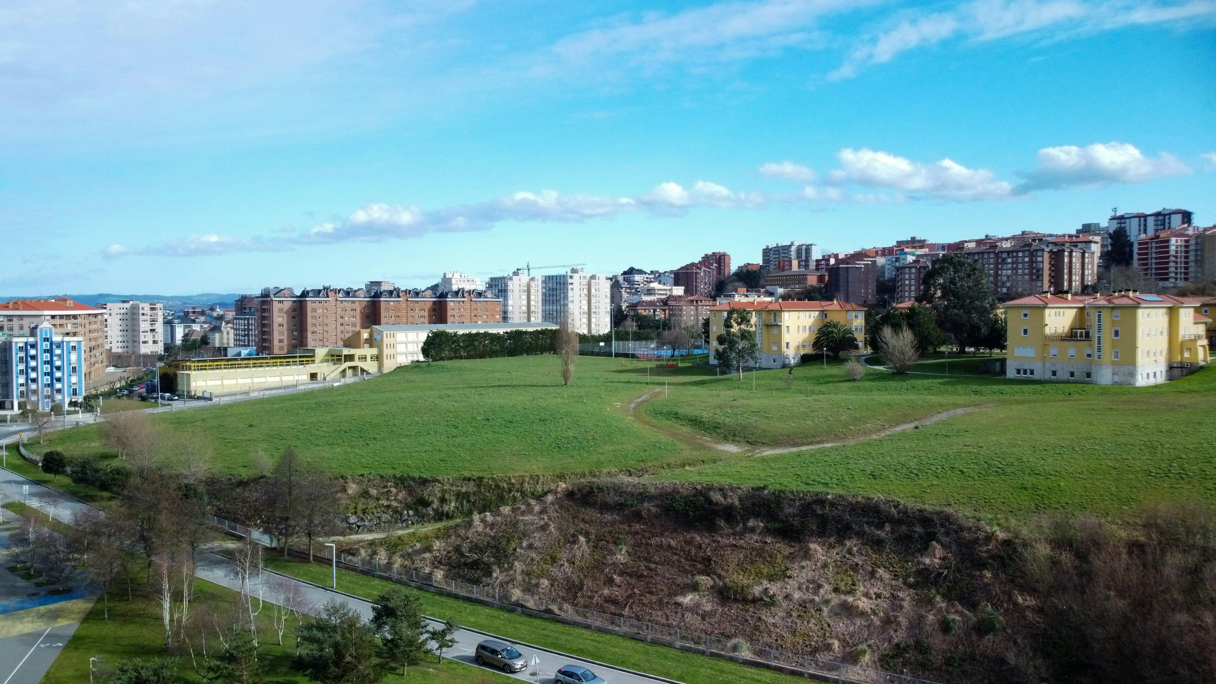 Vast open landscape with blocky terrain, bright daylight, green hills and blue sky, expansive world view