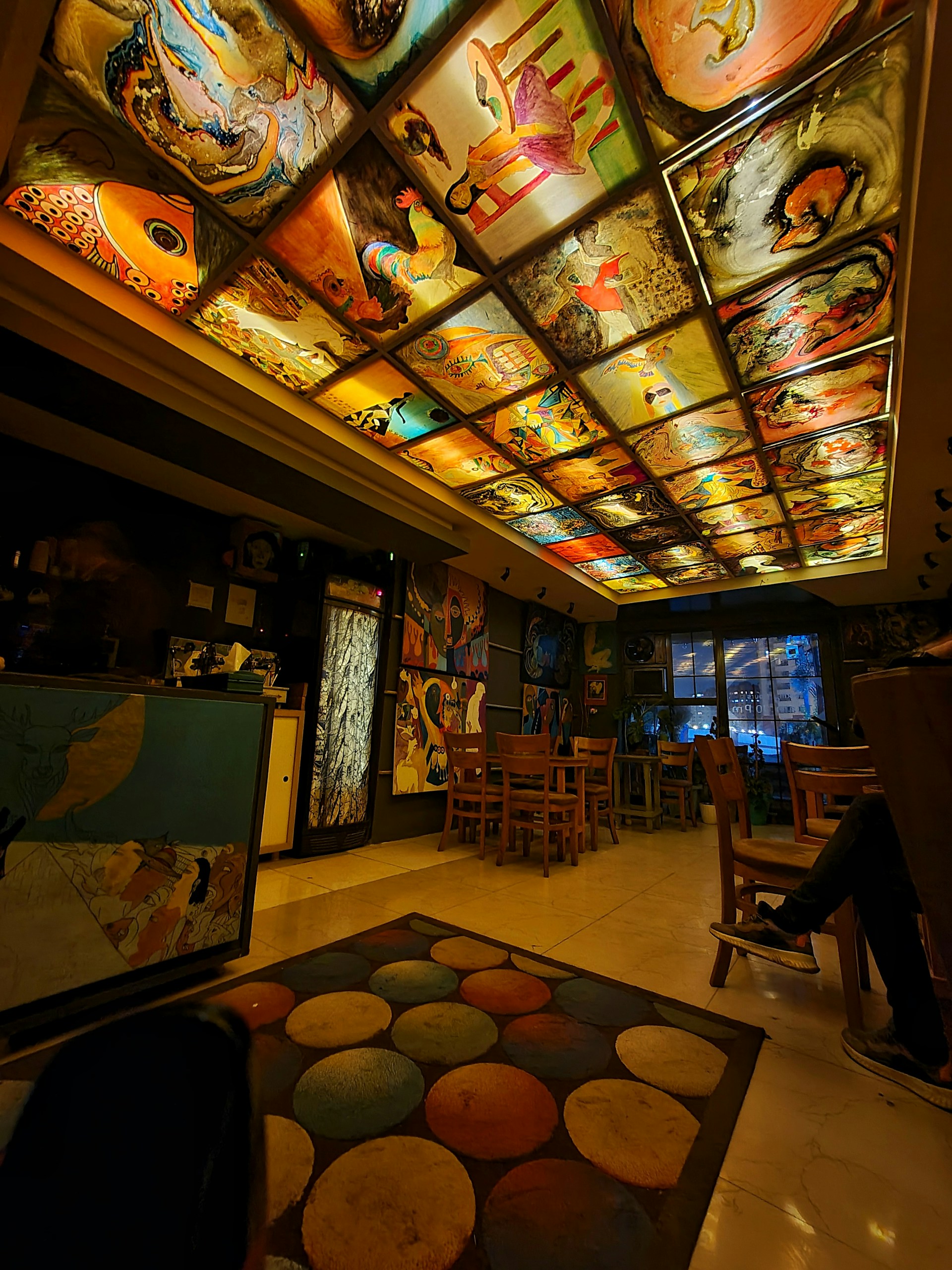 A warmly lit room filled with easels, paint palettes, and glasses of wine, capturing the joyful party atmosphere.