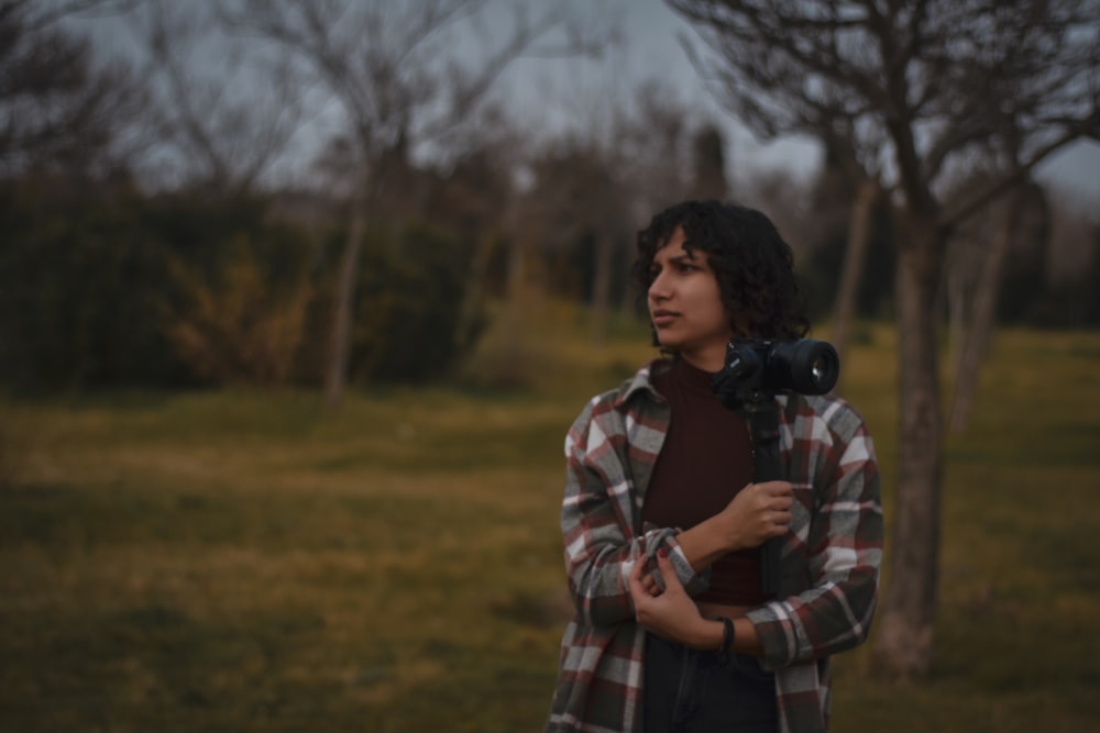 a man standing in a field holding a camera