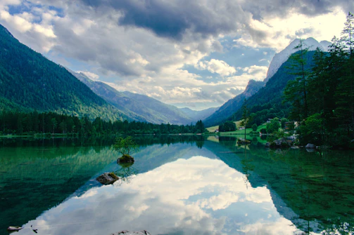 A serene lake reflecting the surrounding mountains and sky, untouched and peaceful.