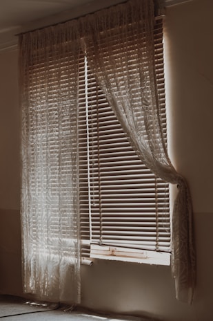 Bedroom window showcasing layered blinds and curtains for privacy and style.