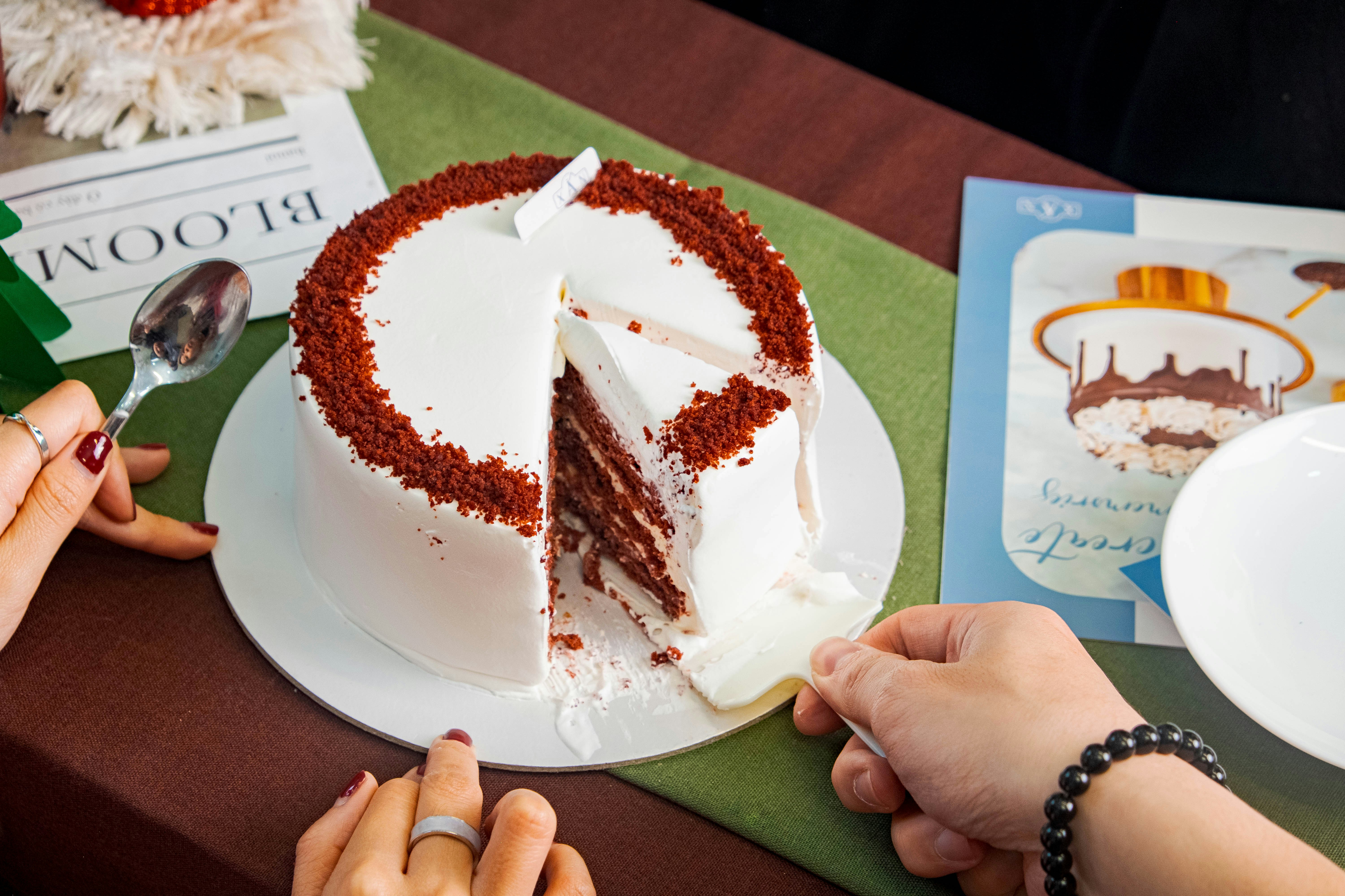 a person cutting a piece of cake with a knife
