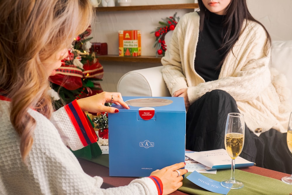 a woman opening a box with a glass of wine