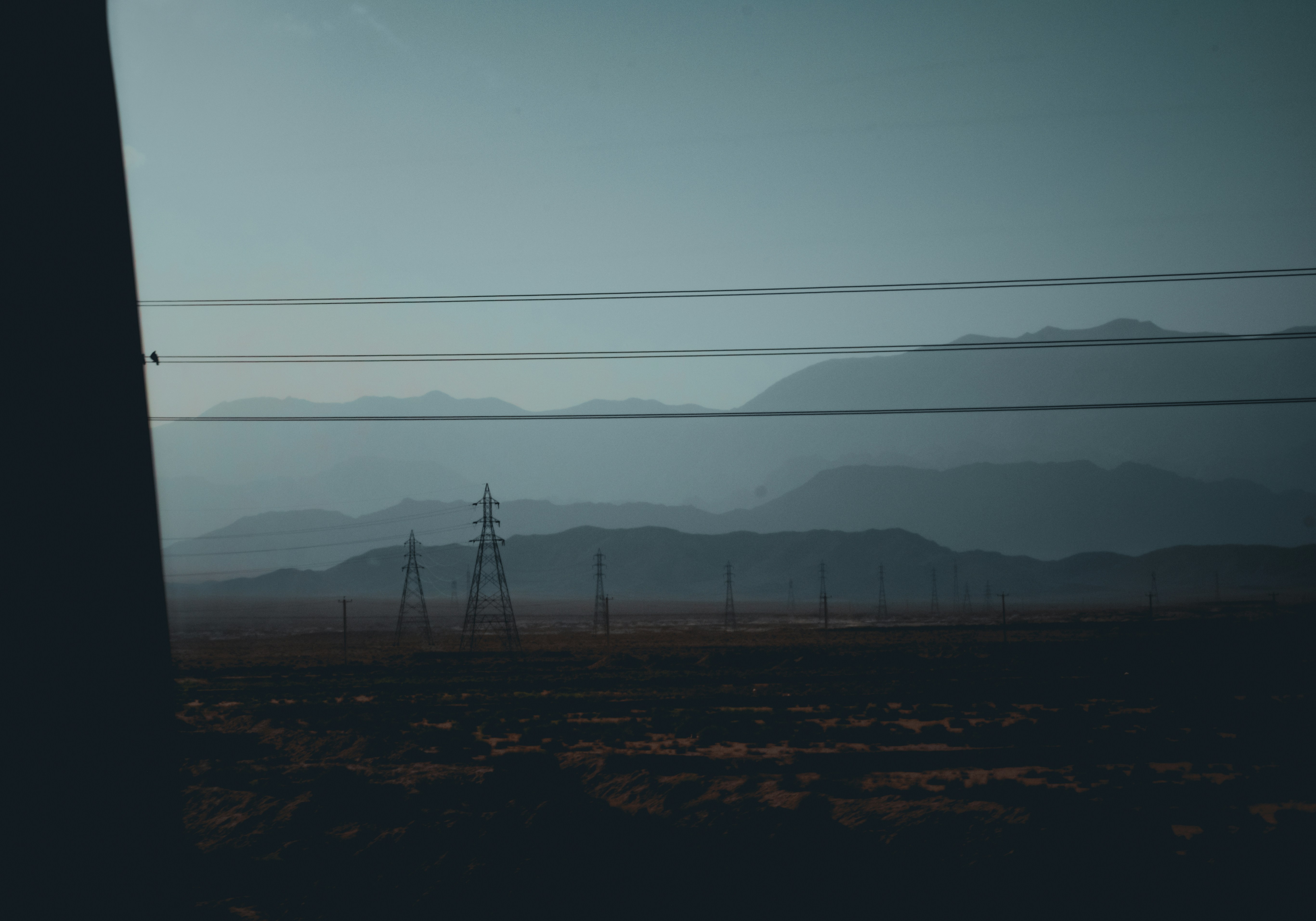 a field with power lines and mountains in the distance
