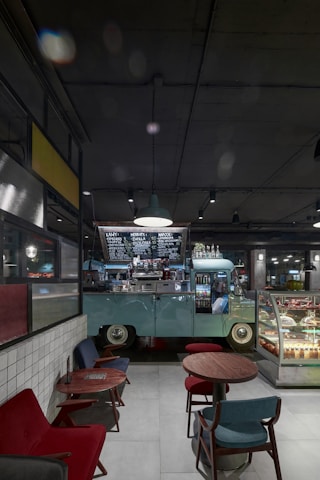 A delivery van parked outside a bustling café, with fresh cakes and desserts being unloaded by friendly staff.