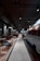 A modern, stylish cafe with an industrial design features a retro van converted into a seating or serving area. Comfortable chairs and small tables line one side, while pendant lights and exposed ceilings create an urban vibe.