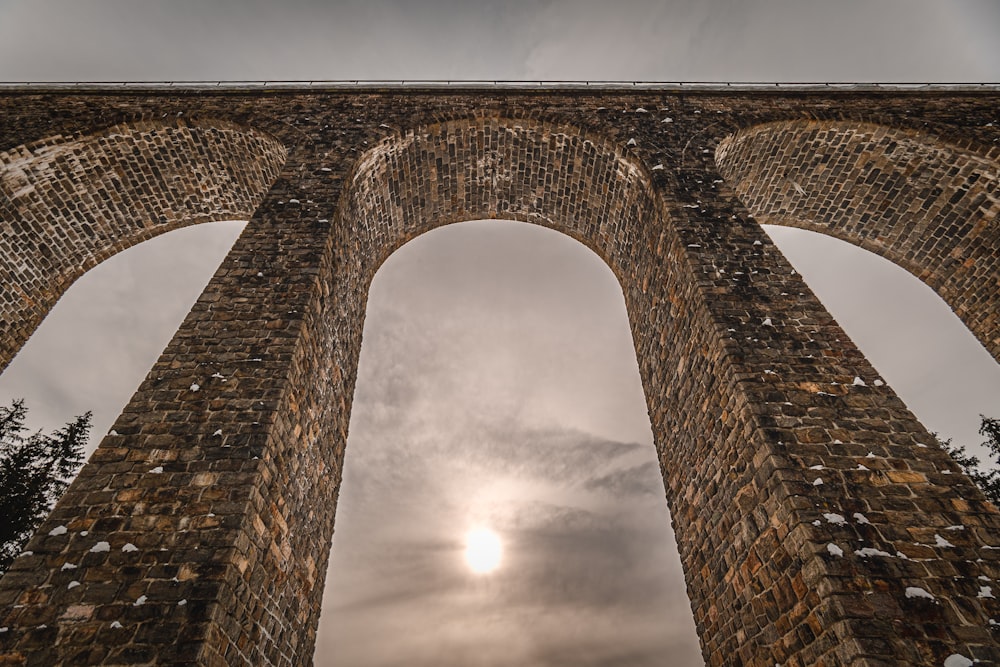 the sun is shining through the arches of a brick bridge