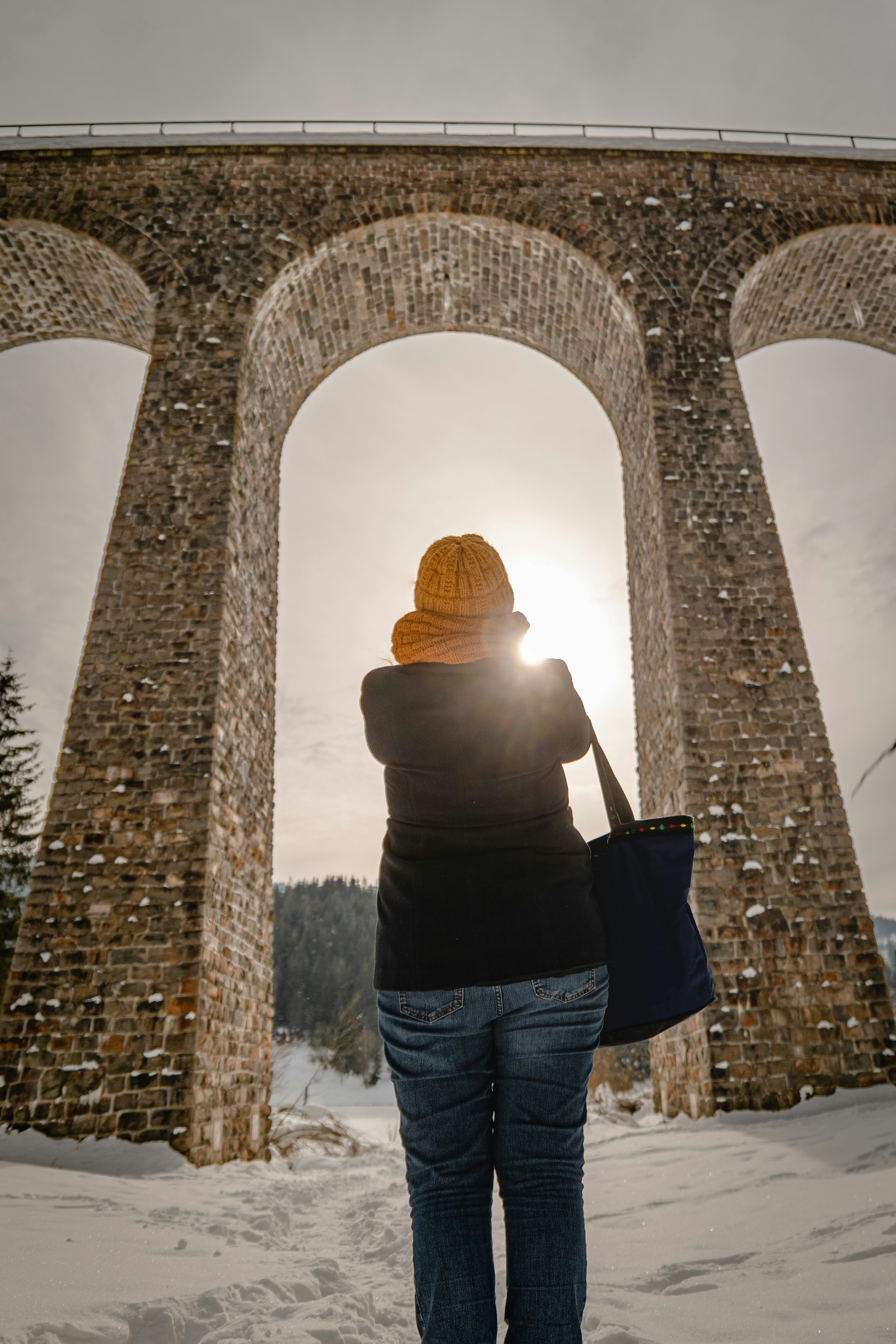 a woman standing in front of a stone arch