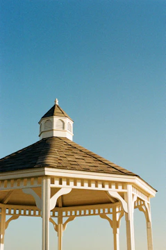 A professional assembling a wooden gazebo in a sunny backyard.