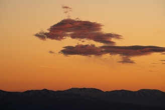 A striking photo of a dramatic storm cloud rolling over a serene landscape at sunset.