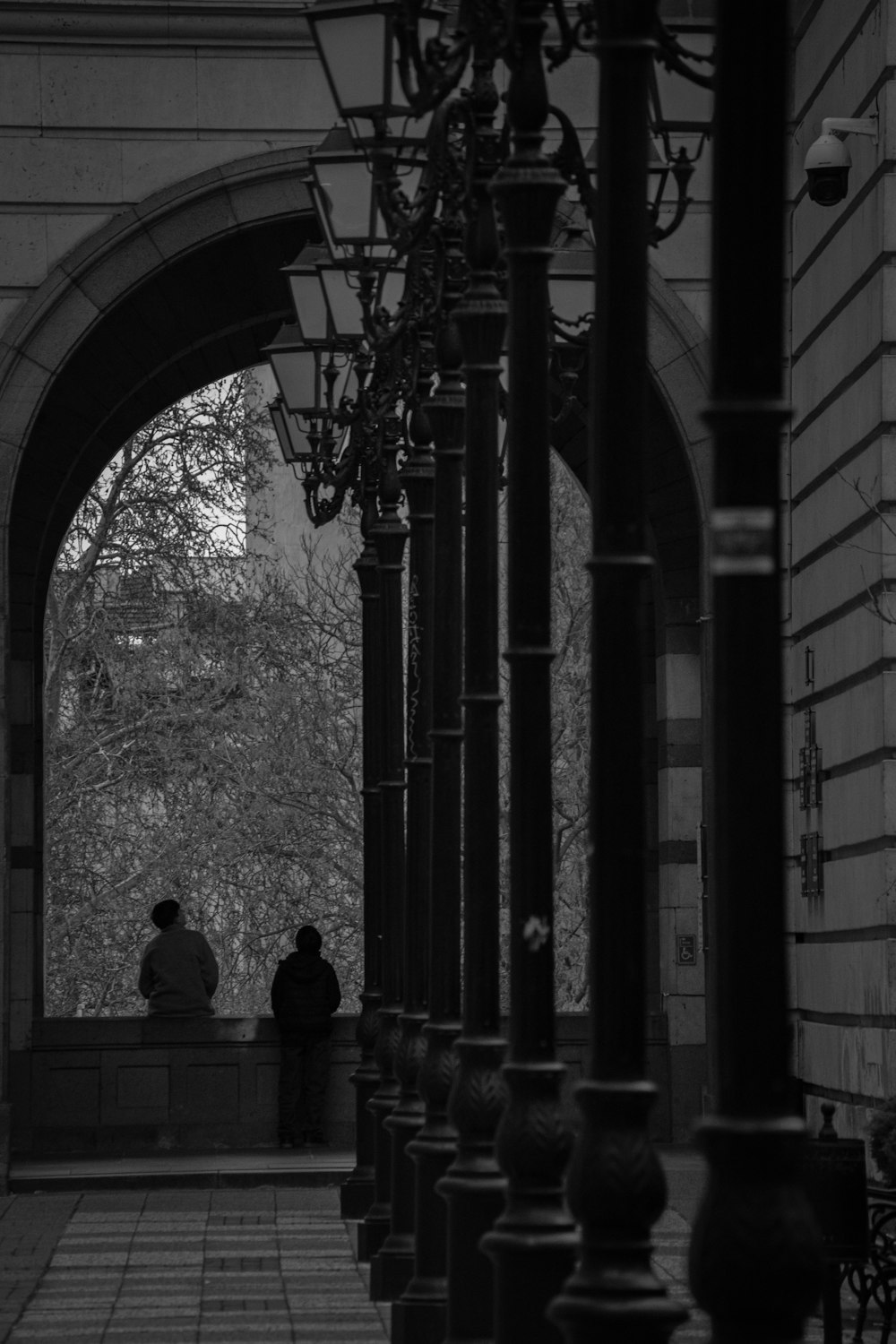 two people sitting on a bench under an archway