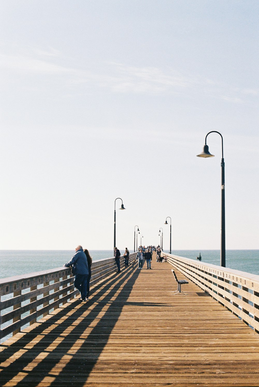 people walking on a pier near the ocean