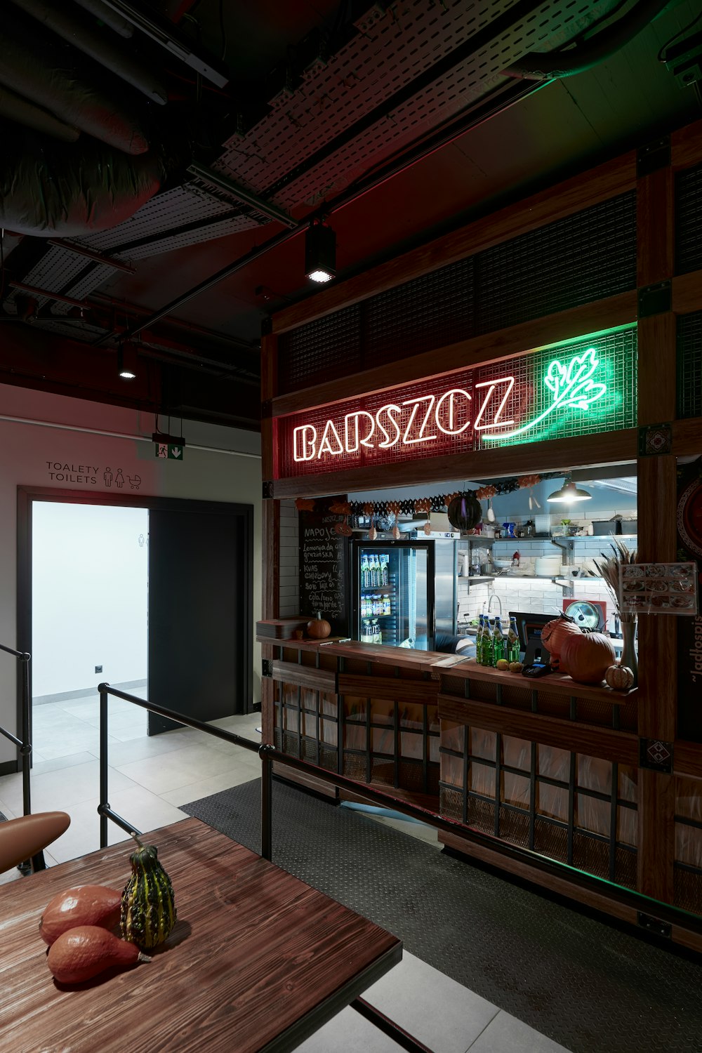 a restaurant with a wooden table and a neon sign