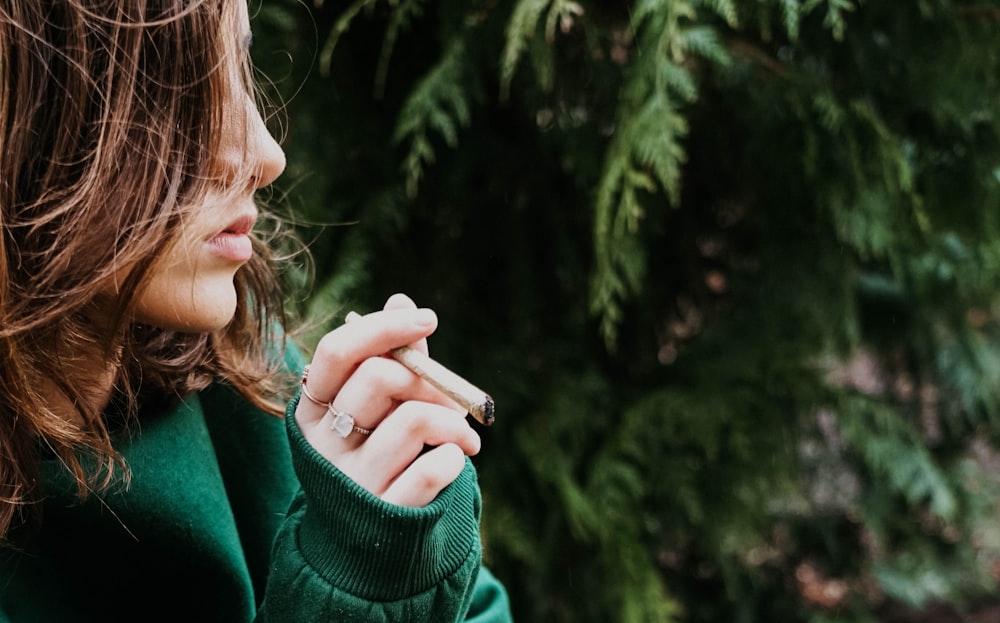 a woman in a green jacket holding a cigarette
