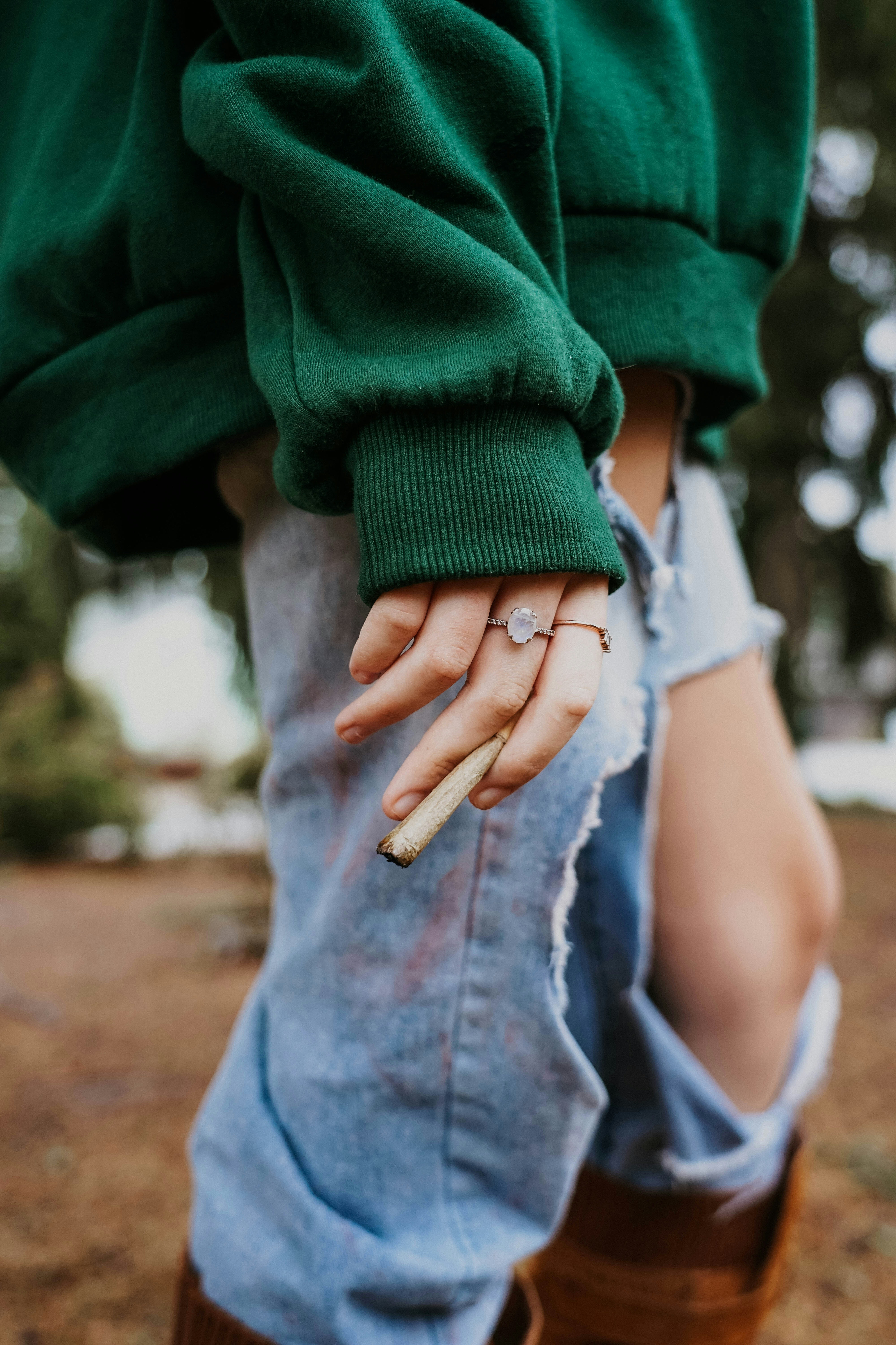 a woman in a green sweater is holding a cigarette