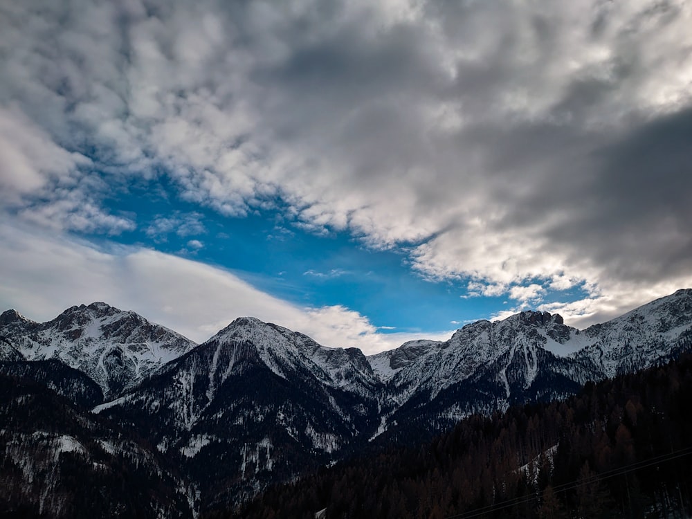 the mountains are covered in snow and clouds