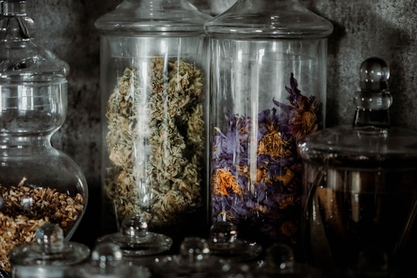 A collection of dried herbs and flowers in small glass jars with natural light.