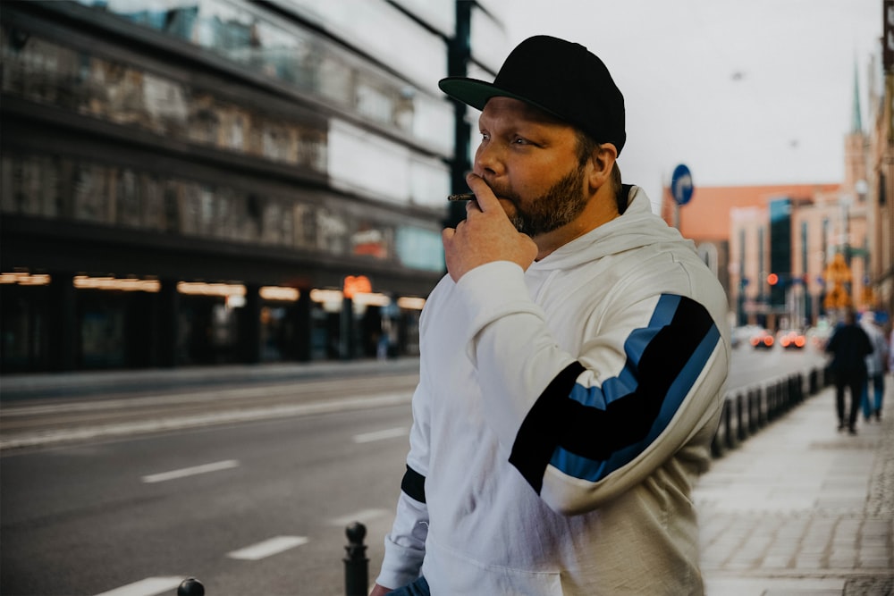 a man standing on the side of a street talking on a cell phone